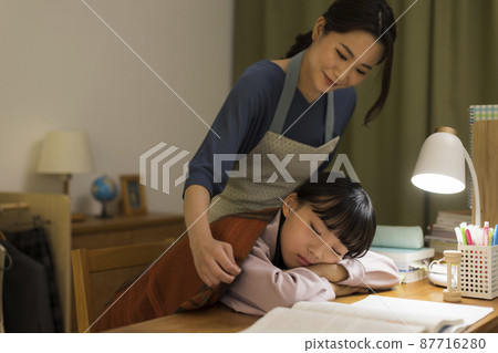 一位母親給在辦公桌前睡著的女兒蓋上毯子 87716280