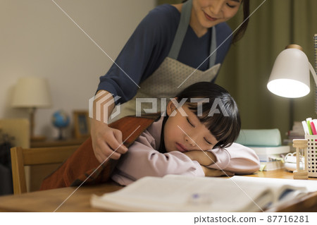 一位母親給在辦公桌前睡著的女兒蓋上毯子 87716281