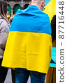 Young man wrapped in the Ukrainian flag in a protest against Russia invasion 87716448