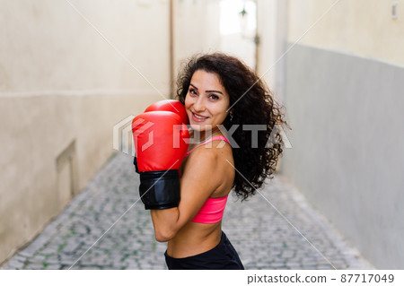 A woman boxer training outdoor - city and nature in background A woman boxer training outdoor - city and nature in background 87717049