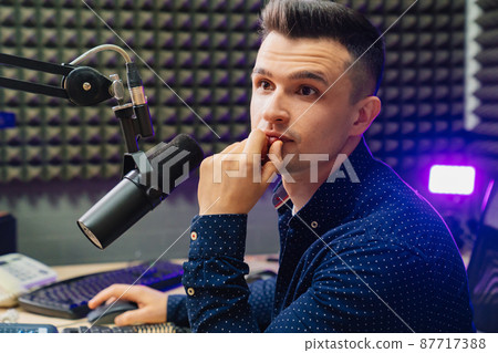 serious radio host broadcasts live reads news on computer screen. serious radio host broadcasts live reads news on computer screen. 87717388