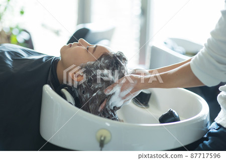 Woman having shampoo at a beauty salon 87717596