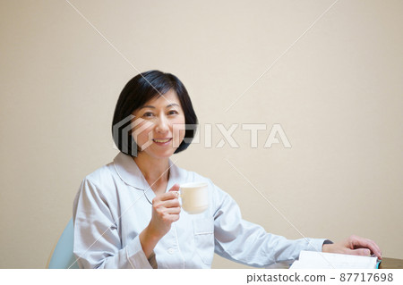 Middle-aged woman in pajamas with a mug Middle-aged woman in pajamas with a mug 87717698