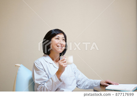 Middle-aged woman in pajamas with a mug Middle-aged woman in pajamas with a mug 87717699