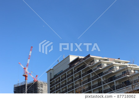 可以看到藍天的城市景觀,一架小飛機的天空,公寓和正在建設中的建築用起重機。 可以看到藍天的城市景觀,一架小飛機的天空,公寓和正在建設中的建築用起重機。 87718002
