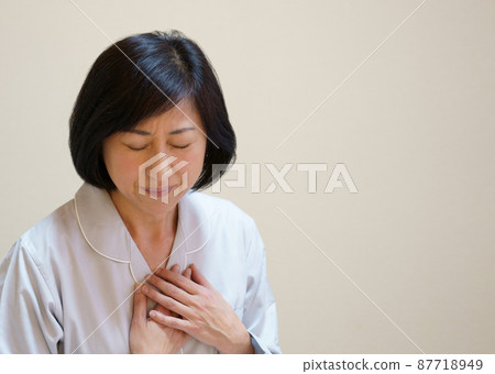 Middle-aged woman holding her breasts in pajamas 87718949