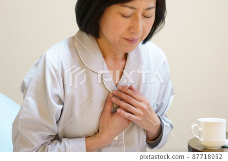 Middle-aged woman holding her breasts in pajamas 87718952