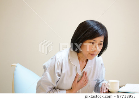 Middle-aged woman holding her breasts in pajamas 87718953