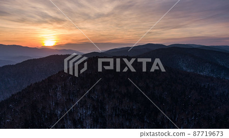 Aerial drone view in mountain forest. Winter landscape. Snowy Fir and Pine trees. Snowy tree branch in a view of the winter forest. Winter landscape, forest, trees covered with frost, snow. 87719673