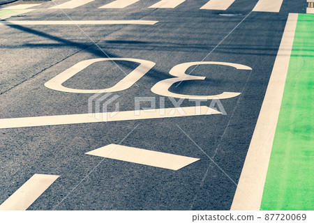 Road markings written on the reflecting road surface Zone 30 and stop lines and pedestrian crossings Warm and cool emphasis 87720069
