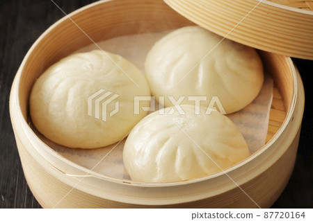 Hot meat bun freshly steamed in a bamboo steamer 87720164