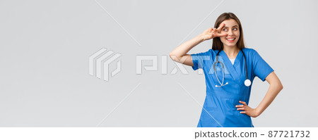 Medical workers, healthcare, covid-19 and vaccination concept. Cheerful and energized young female doctor, pretty nurse in blue scrubs, stethoscope, show peace near eye and smiling upbeat 87721732