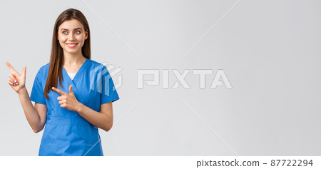 Healthcare workers, prevent virus, insurance and medicine concept. Smiling pretty nurse or doctor in blue scrubs, pointing fingers left and looking at baner with pleased grin, grey background 87722294