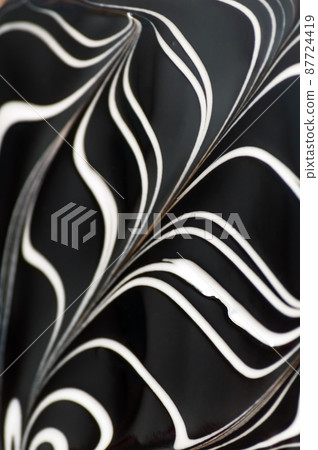 Abstract vertical background. White curved lines on a dark brown background. Striped chocolate pattern. Icing on the cake Abstract vertical background. White curved lines on a dark brown background. Striped chocolate pattern. Icing on the cake 87724419