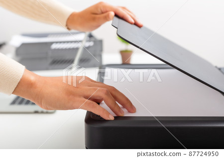 Woman hand putting white paper in printer, scanner,  copy machine, office document, photocopier. 87724950