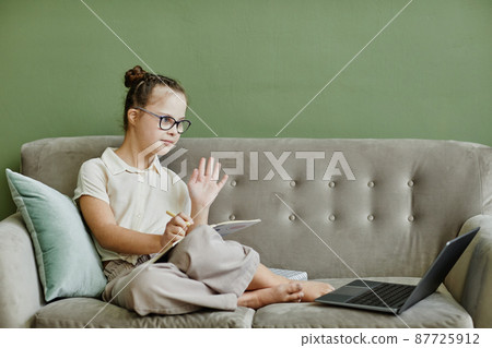Girl with Down Syndrome using Laptop at Home 87725912