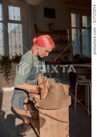 Woman potter shaping clay on pottery wheel in atelier Woman potter shaping clay on pottery wheel in atelier 87725954