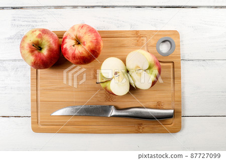 Cut red apple and stainless steel knife on a bamboo cutting board Cut red apple and stainless steel knife on a bamboo cutting board 87727099