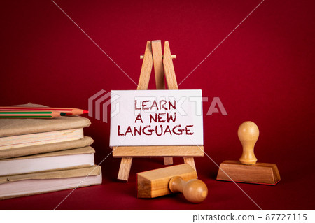 Learn a New Language. Stack of books and stamps on a red background Learn a New Language. Stack of books and stamps on a red background 87727115