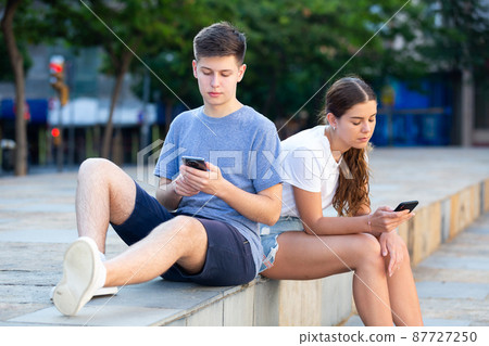 Teenagers are playing on smartphone on street Teenagers are playing on smartphone on street 87727250
