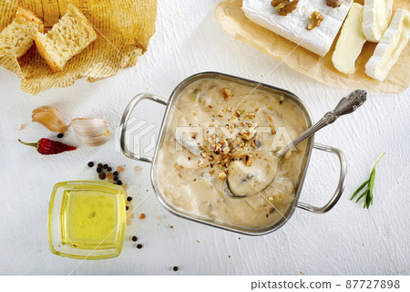 Melting camamber in pan with mushrooms, basil and garlic croutons, on a wooden table in rustic style 87727898