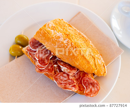 Spanish breakfast - smoked sausage fuet sandwich and olives closeup 87727914