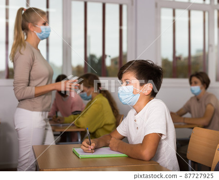 Schoolboy in mask sitting in classroom during lesson 87727925