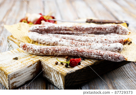 Traditional white salami sausage, sliced salami isolated on white background. Whole dry salami sausage stick. 87729373