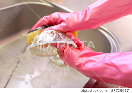 Wash dishes with rubber gloves 87729617
