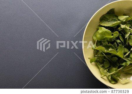 Overhead view of leaf vegetables in bowl on table with copy space 87730329