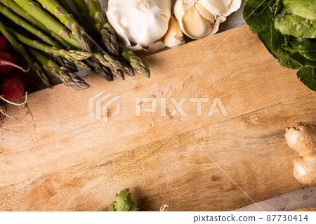High angle view of wooden cutting board by vegetables and spices on table 87730414