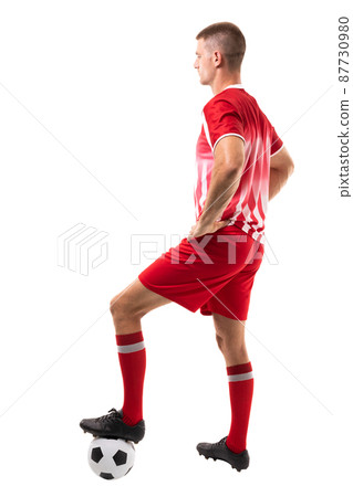 Full length side view of young male caucaisan soccer player stepping on ball over white background 87730980