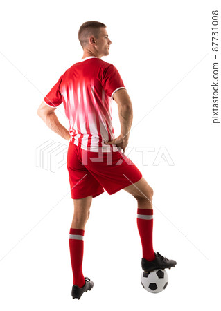 Full length rear view of young male soccer player stepping on ball over white background 87731008