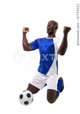 Excited male african american soccer athlete kneeling while celebrating goal over white background Excited male african american soccer athlete kneeling while celebrating goal over white background 87731012