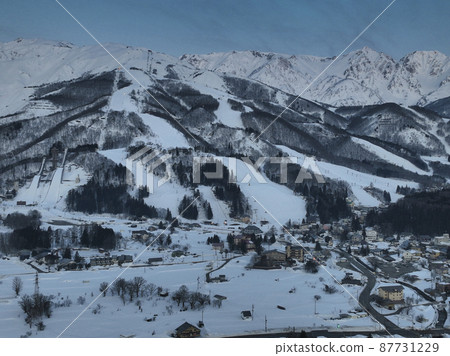 Beautiful Hakuba mountain range before sunrise and Hakuba village / Happoone ski resort Hakuba village, Nagano prefecture (aerial view by drone) 87731229