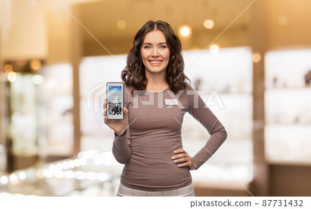 female shop assistant with qr code on smartphone female shop assistant with qr code on smartphone 87731432