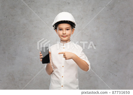 little boy in construction helmet with smartphone 87731650