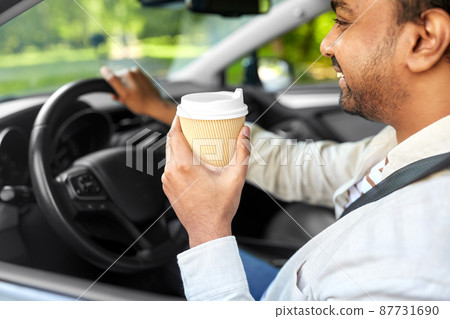 happy indian man or driver with coffee driving car 87731690