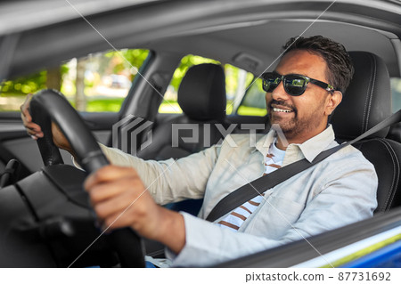 smiling indian man in sunglasses driving car 87731692