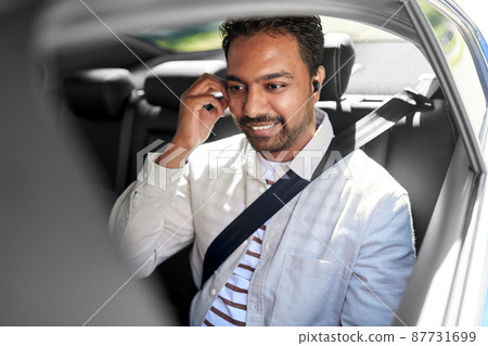 indian male passenger with earphones in taxi car 87731699