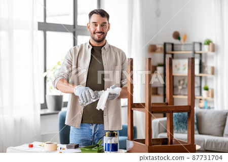 man applying solvent to rag for cleaning old table 87731704