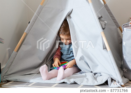 girl playing with fidget toy in teepee at home girl playing with fidget toy in teepee at home 87731766