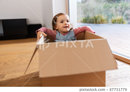 little baby girl sitting in cardboard box at home 87731779