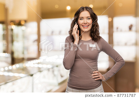 happy female shop assistant calling on smartphone happy female shop assistant calling on smartphone 87731787