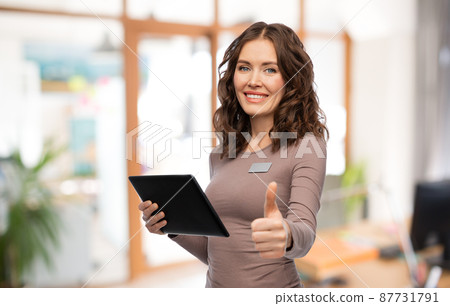 woman with tablet pc showing thumbs up at office 87731791