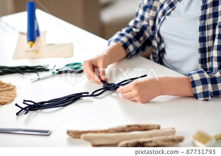 woman making macrame and knotting cords 87731793