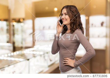 happy female shop assistant calling on smartphone happy female shop assistant calling on smartphone 87731806