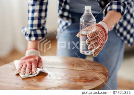 woman degreasing old table surface with solvent 87731821