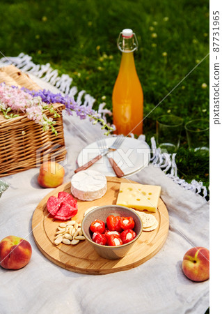 food, drinks and basket on picnic blanket on grass food, drinks and basket on picnic blanket on grass 87731965