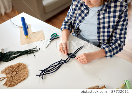 woman making macrame and knotting cords 87732011